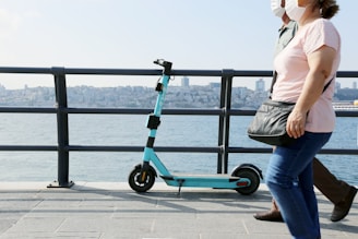 Two-person 2000w electric scooter with electric blue accents cruising along a city road.