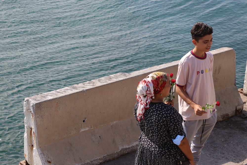 man and woman standing beside body of water during daytime