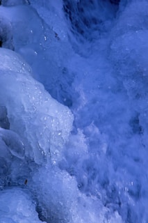 Close-up of icy glacial water flowing over smooth rocks, capturing the purity and freshness of nature.