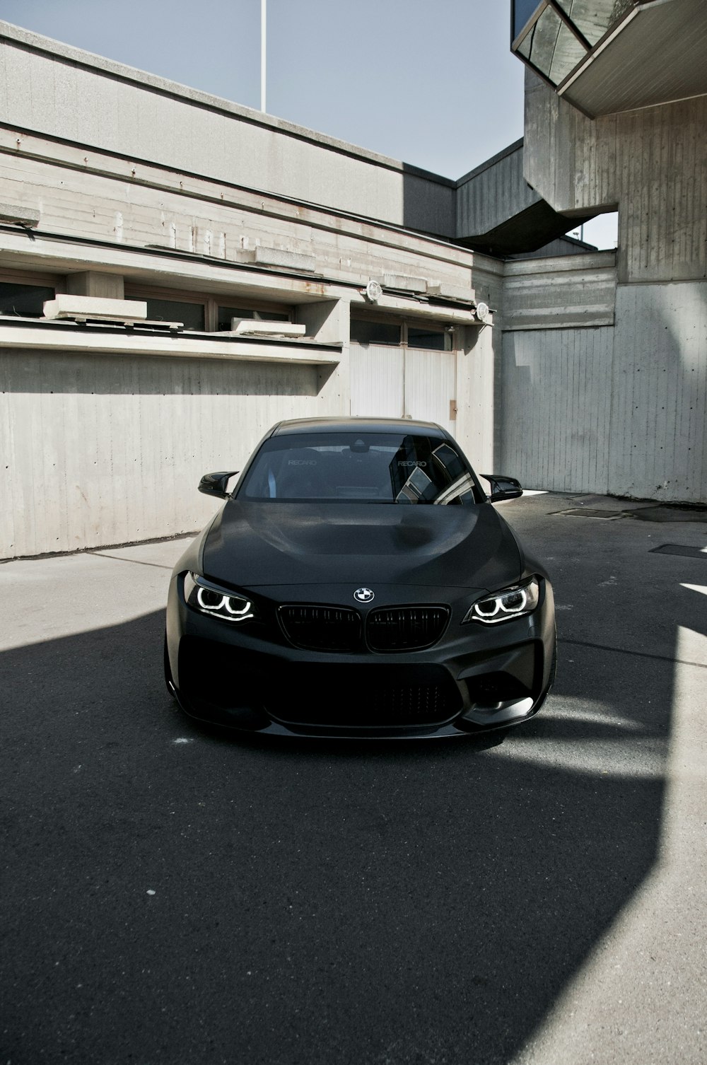 Auto BMW nera parcheggiata sul pavimento di cemento grigio durante il giorno