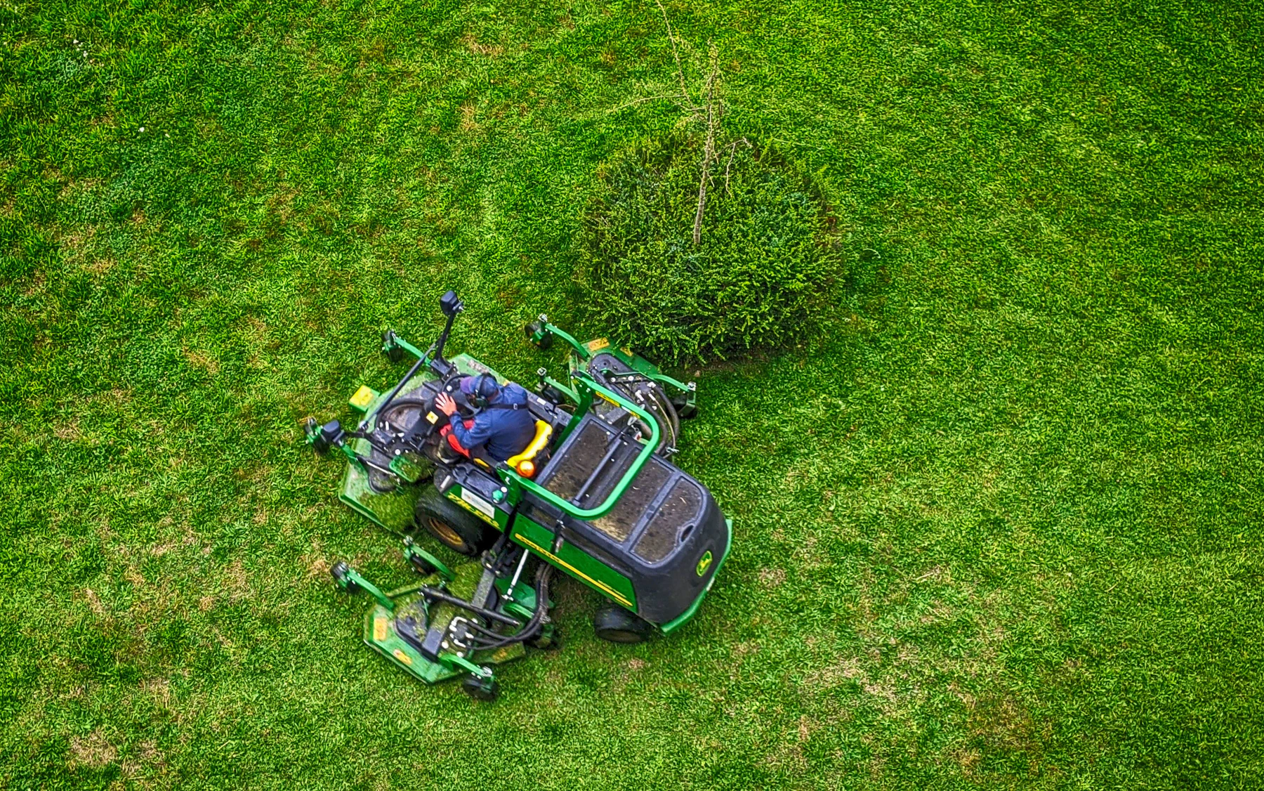 Ride-on lawn mower cutting a green residential lawn