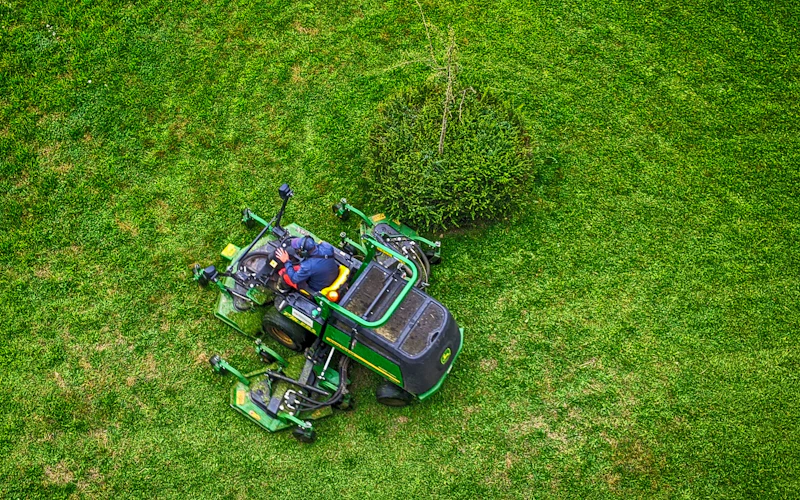 Aerial view of riding mower on lush striped lawn