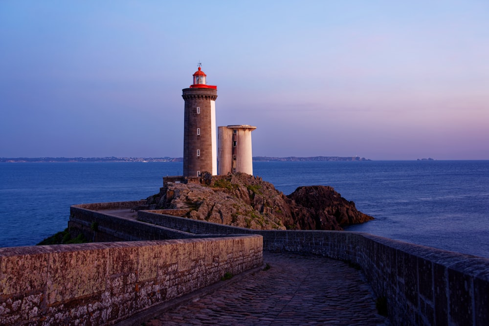 farol branco perto do corpo de água durante o dia