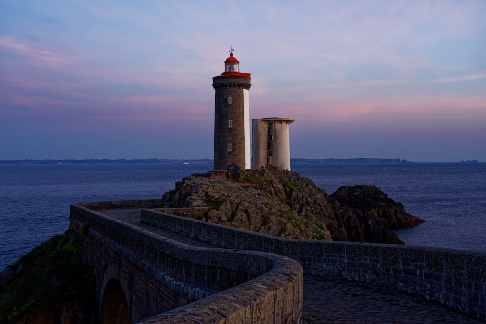 farol branco e vermelho perto do corpo de água durante o dia