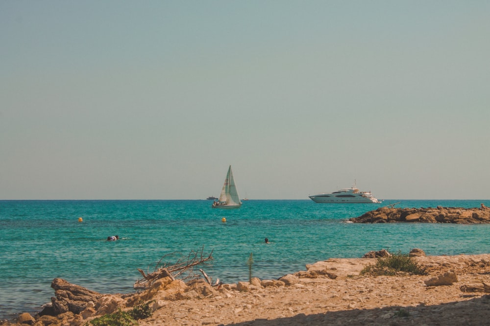 white sail boat on sea shore during daytime