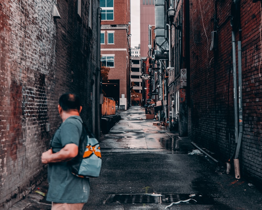 man in gray t-shirt and gray shorts walking on street during daytime