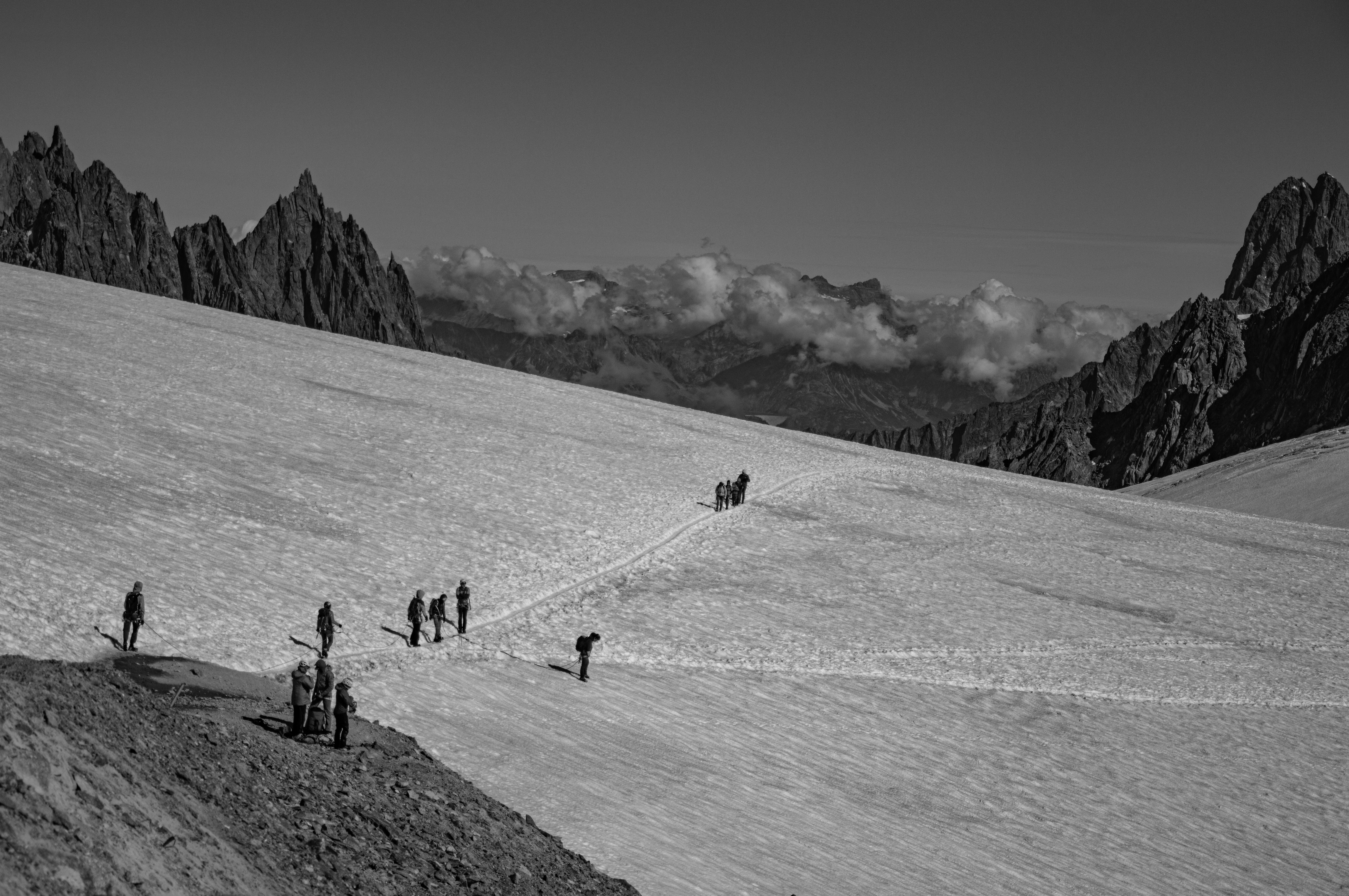 grayscale photo of people walking on snow covered field