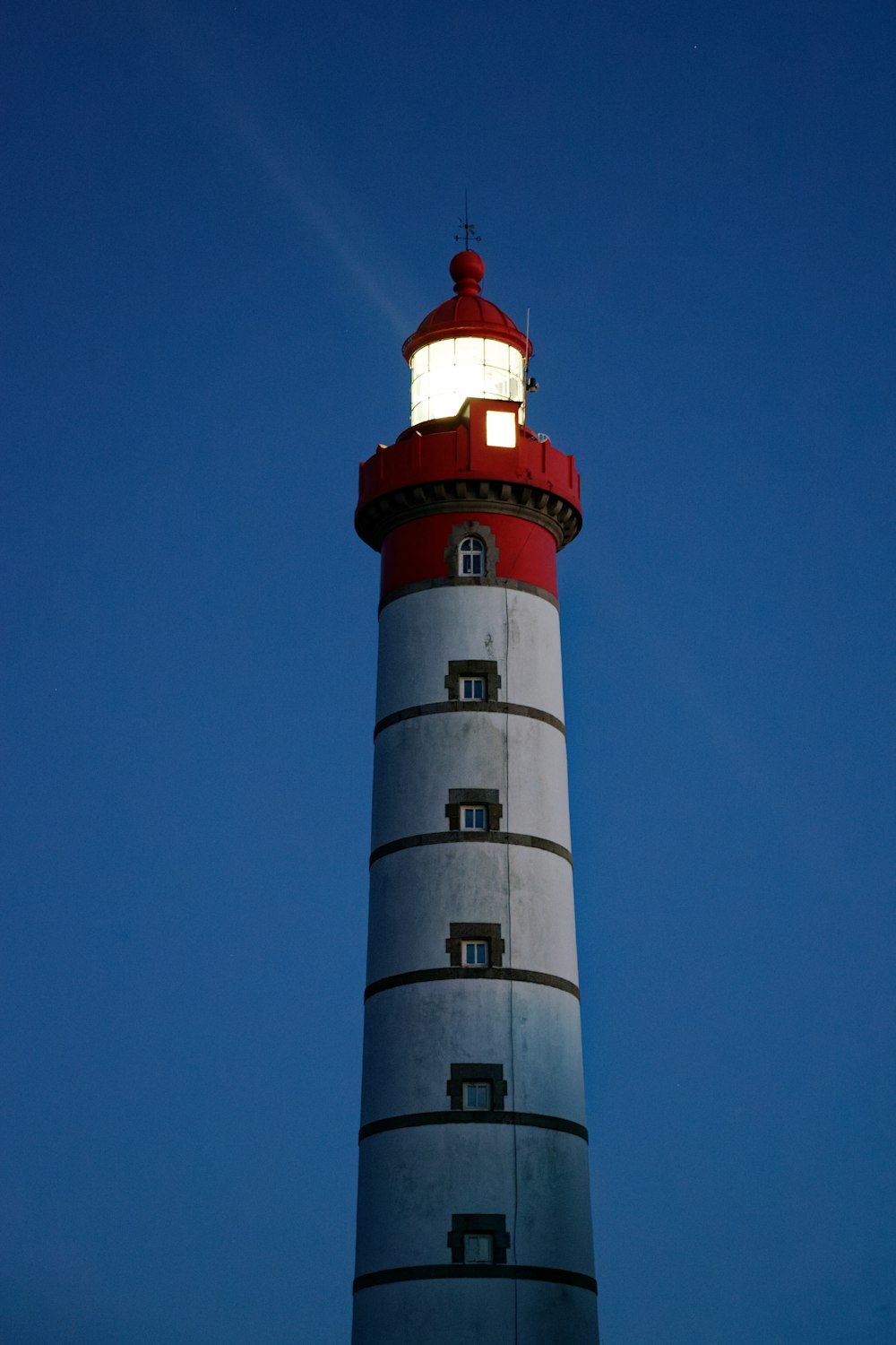 Faro rojo y blanco bajo el cielo azul durante el día