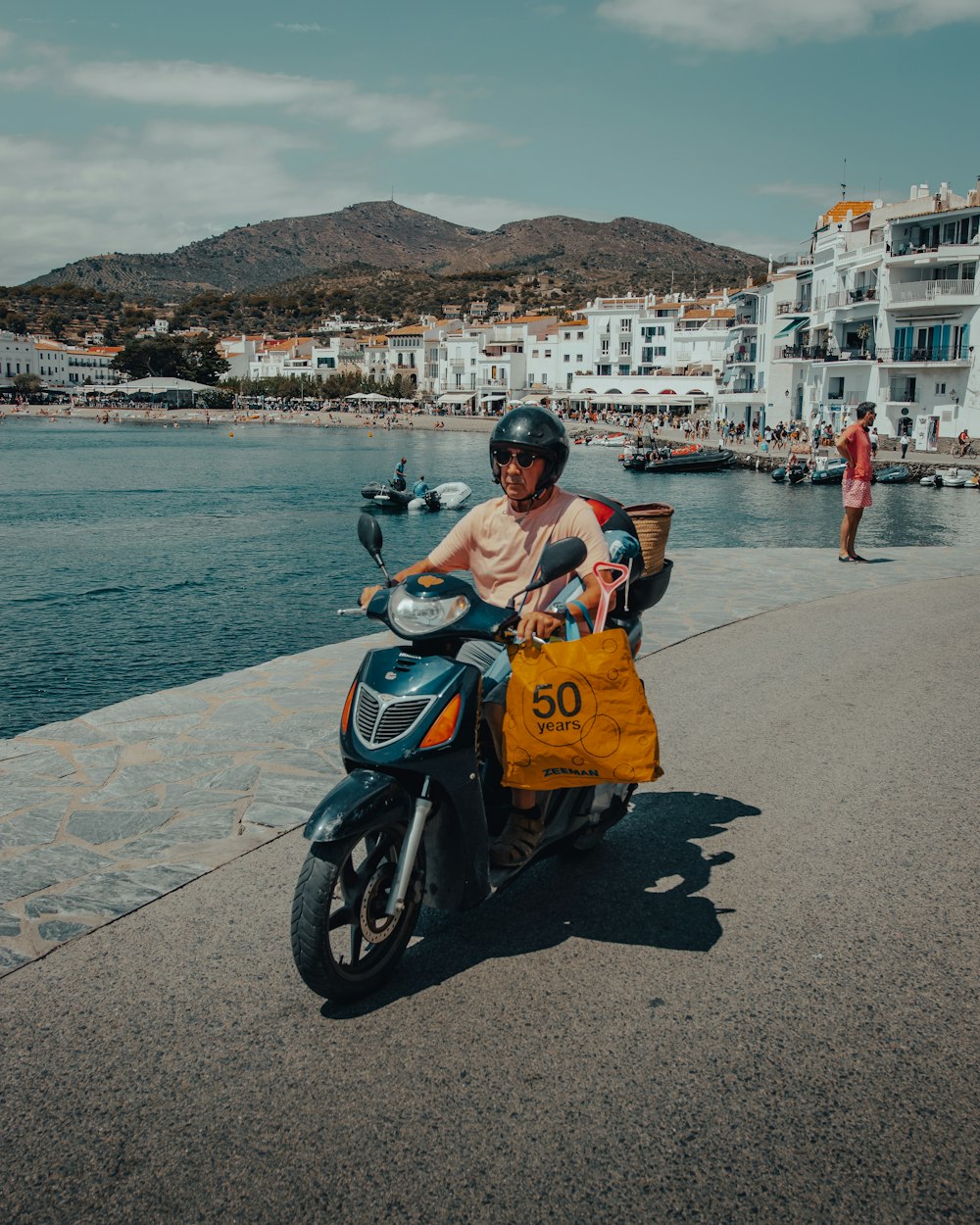  woman in orange dress sitting on black motor scooter near body of water during daytime