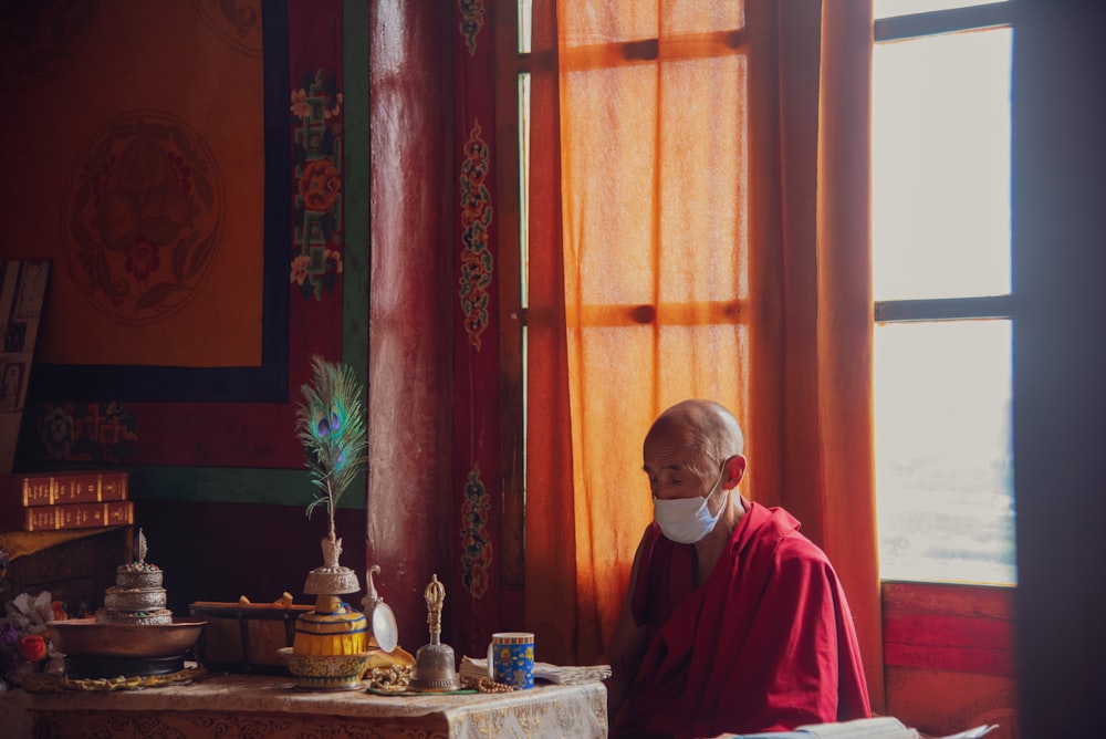 man in red and white thobe sitting on chair