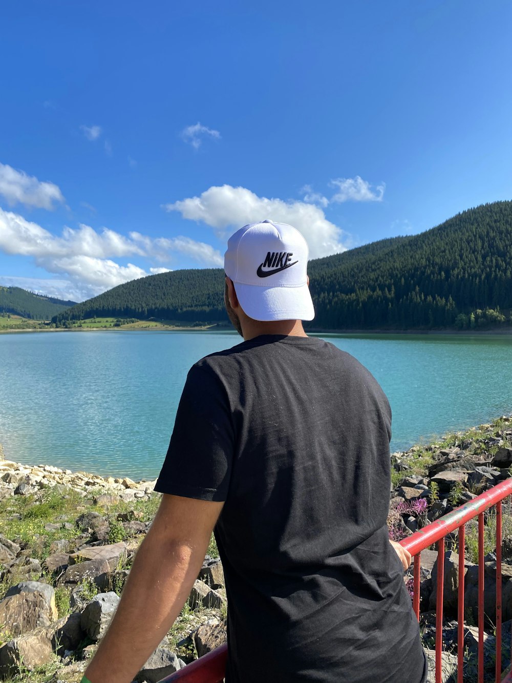 man in grey crew neck t-shirt and white cap standing on rocky shore during daytime
