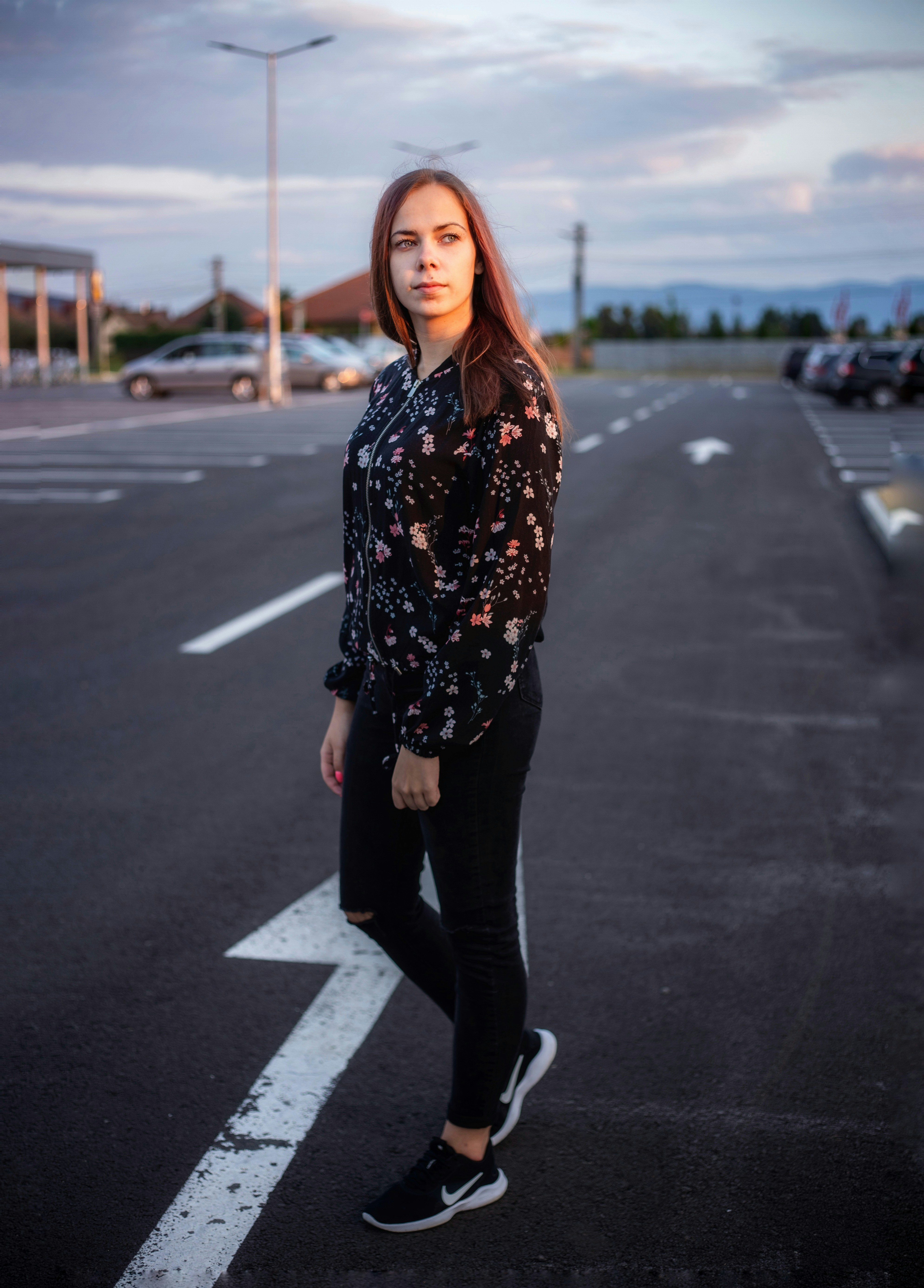 woman in black and white floral long sleeve shirt and black pants standing on road during