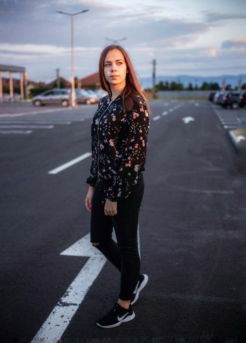 woman in black and white floral long sleeve shirt and black pants standing on road during
