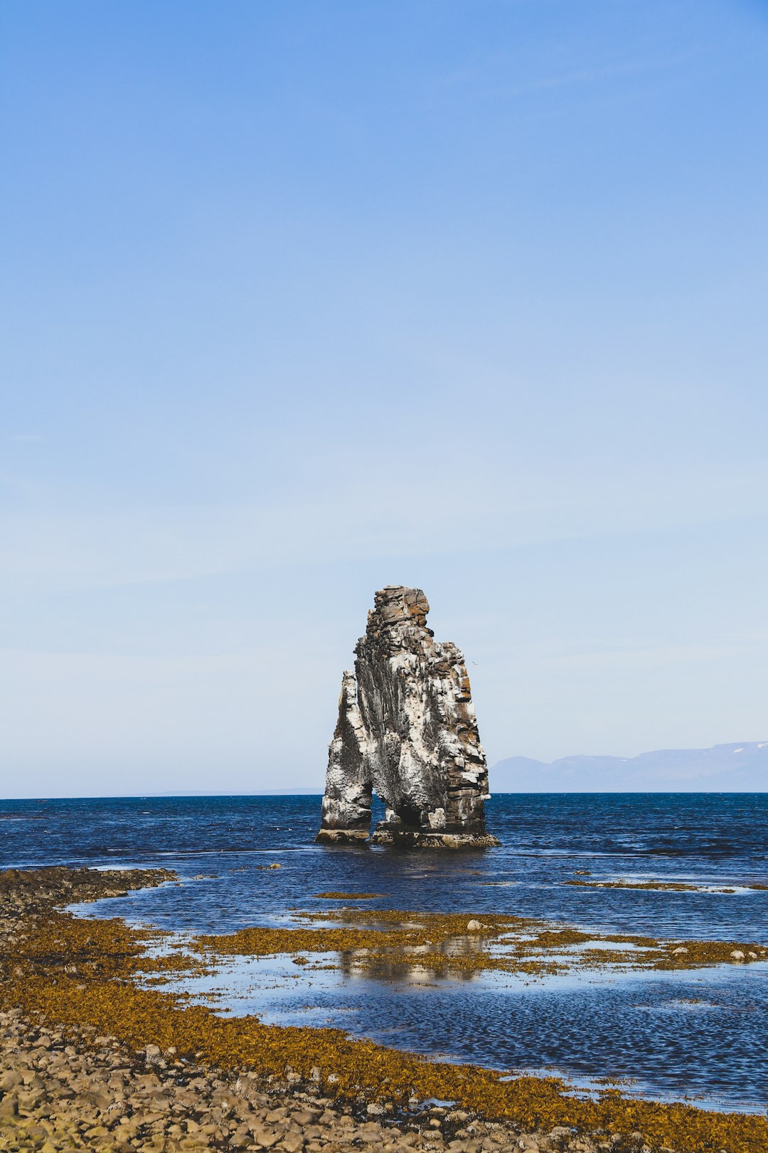 gray rock formation on sea under blue sky during daytime