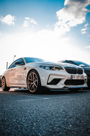 A sleek white car parked under a bright blue sky with yellow accents on the showroom floor