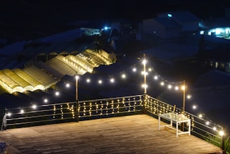A wooden deck overlooking a garden, featuring built-in benches and lighting.