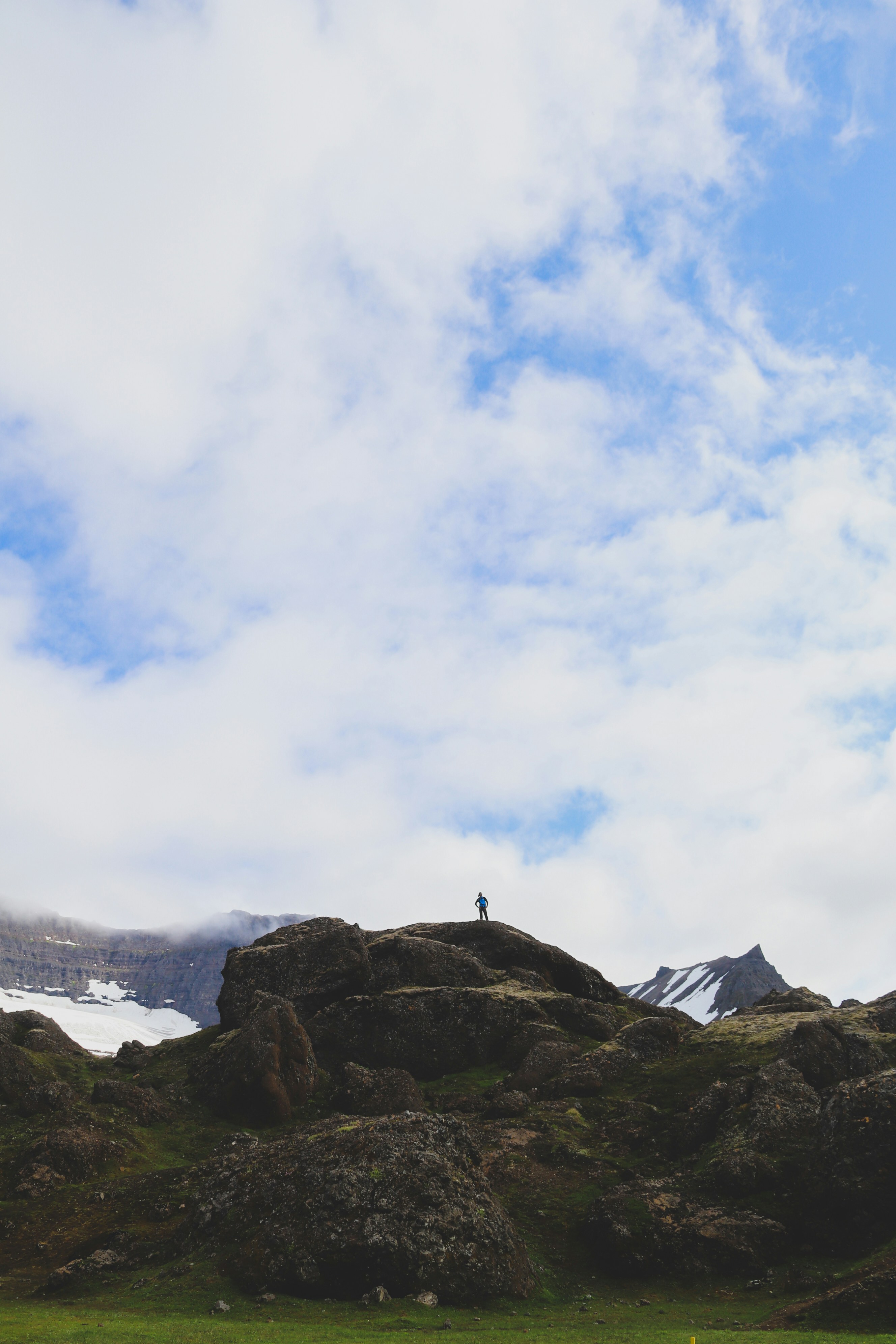 Person Standing On Rock Formation Under White Clouds During Daytime Photo Free Blue Image On Unsplash