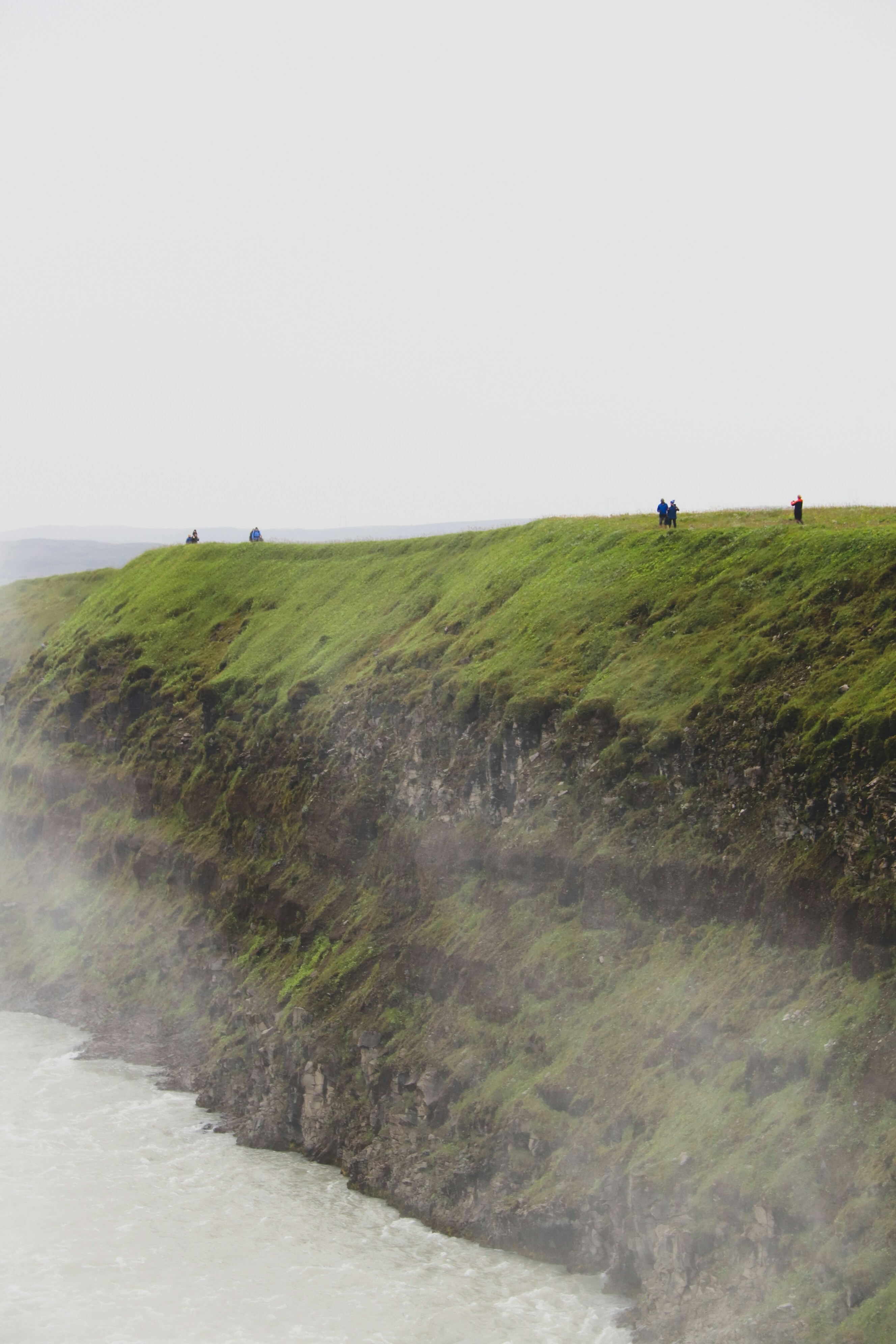 Persona in piedi sul campo di erba verde vicino allo specchio d'acqua durante il giorno