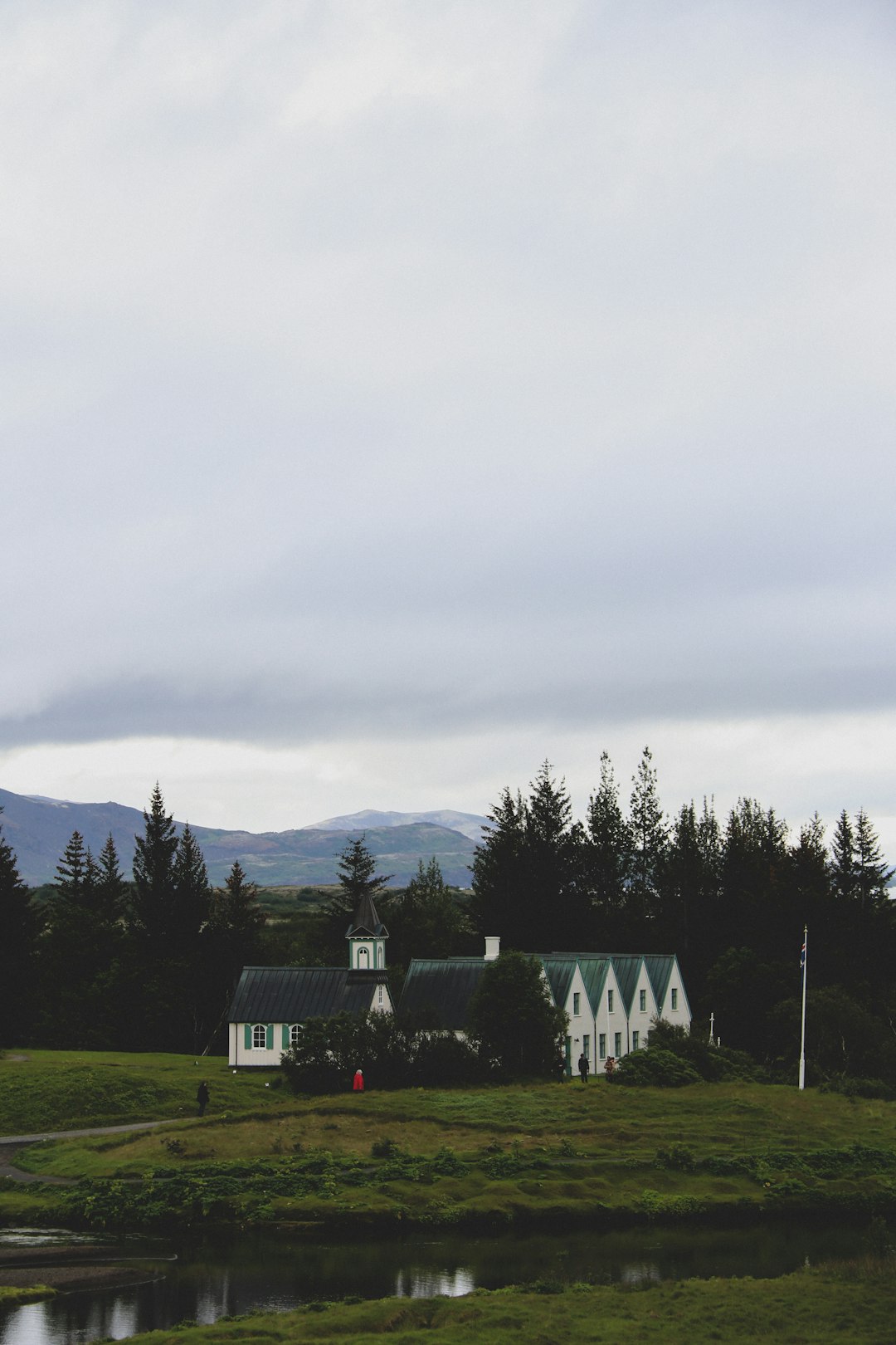 white and black house near green trees and mountain under white clouds during daytime
