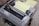 An Epson dot matrix printer with control buttons and a stack of continuous form paper loaded. The printer appears to be in an office or workspace setting.