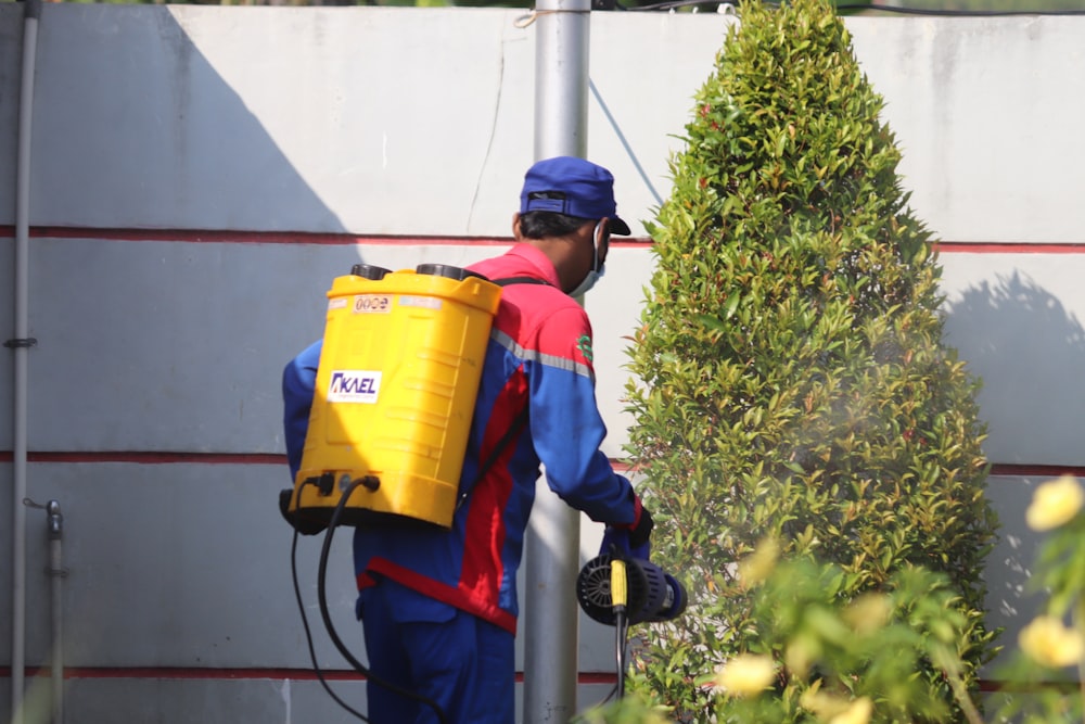 woman in blue and red jacket holding yellow plastic bucket