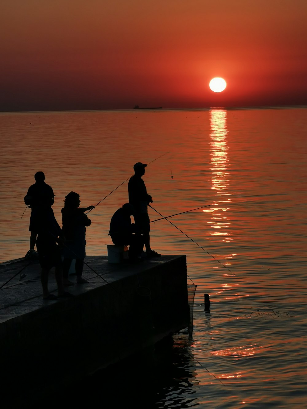 silhouette of people standing on dock during sunset