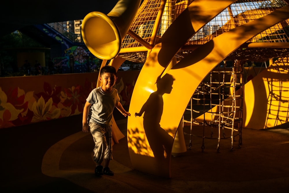 a young boy standing next to a yellow sculpture