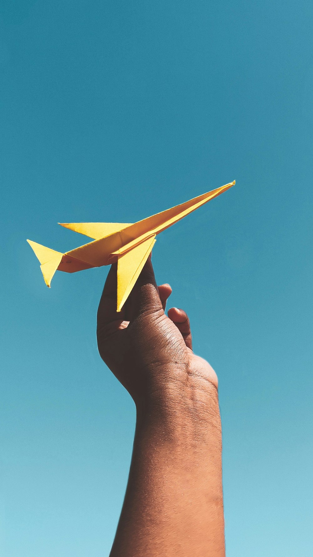 person holding yellow paper plane