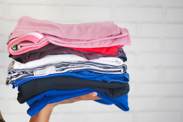 Close-up of a red and black casual shirt neatly folded on a light pink background.