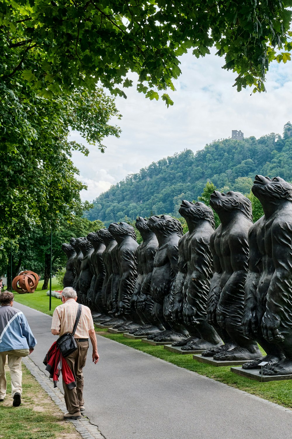 woman in white shirt walking on pathway near black statue during daytime