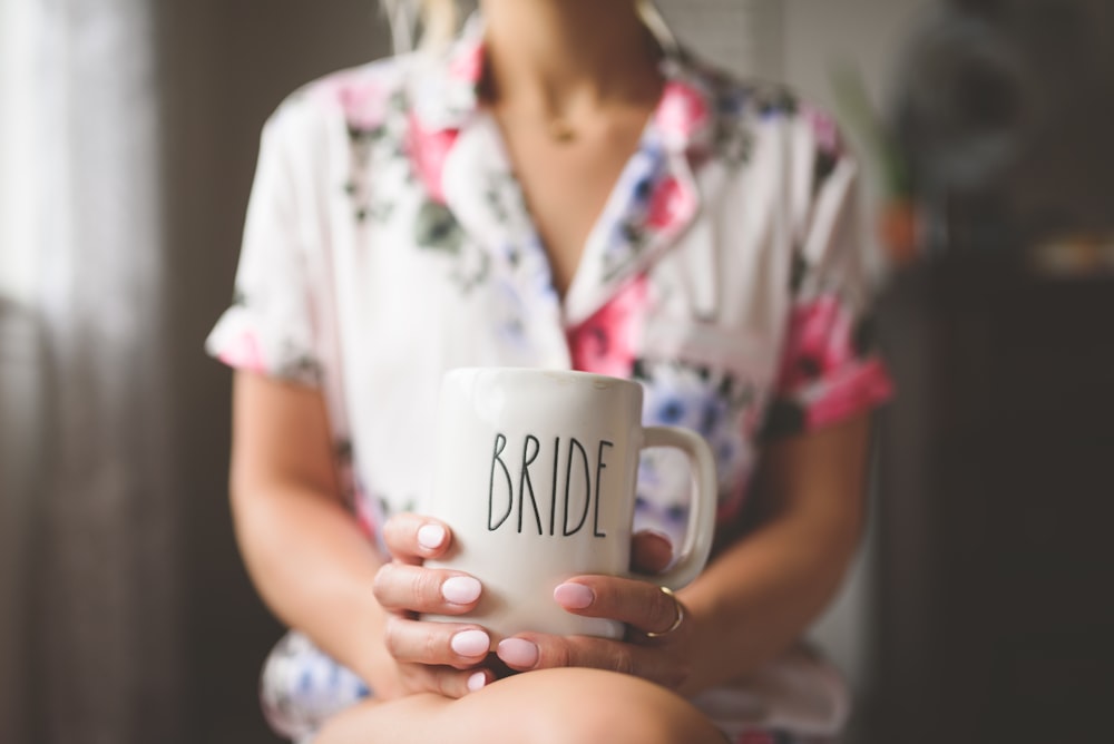 woman in white and pink floral button up shirt holding white ceramic mug