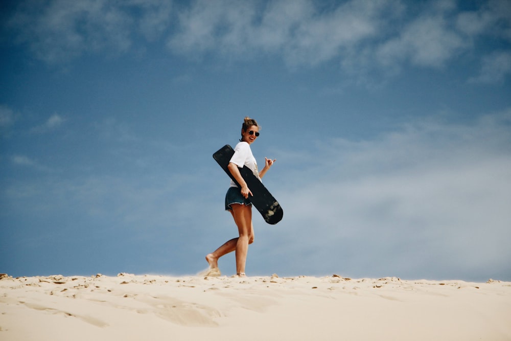 woman in black dress running on sand during daytime