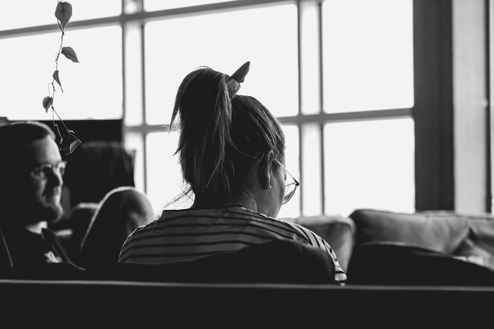 grayscale photo of woman sitting on sofa