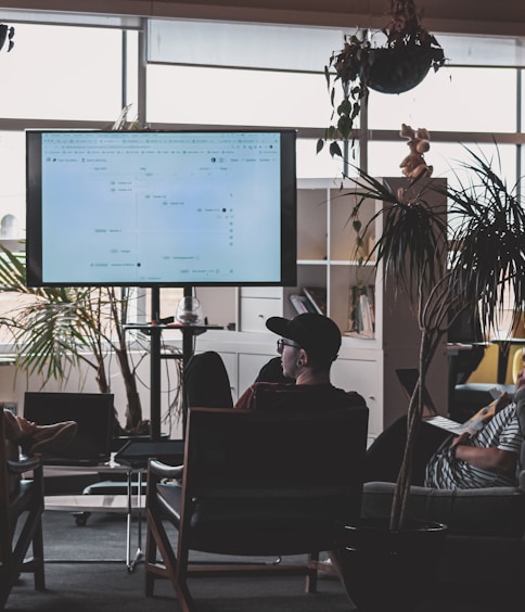 man in black shirt sitting on chair in front of computer monitor