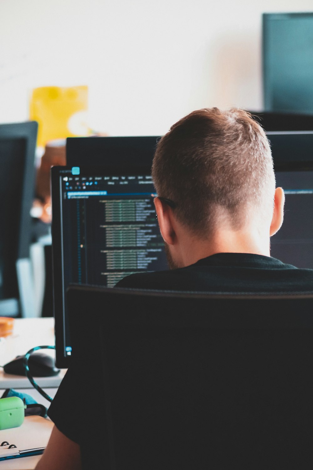 uomo in camicia nera che si siede davanti al computer