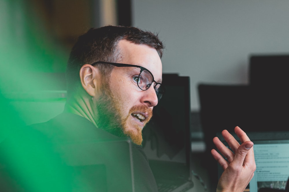 man in green shirt wearing black framed eyeglasses