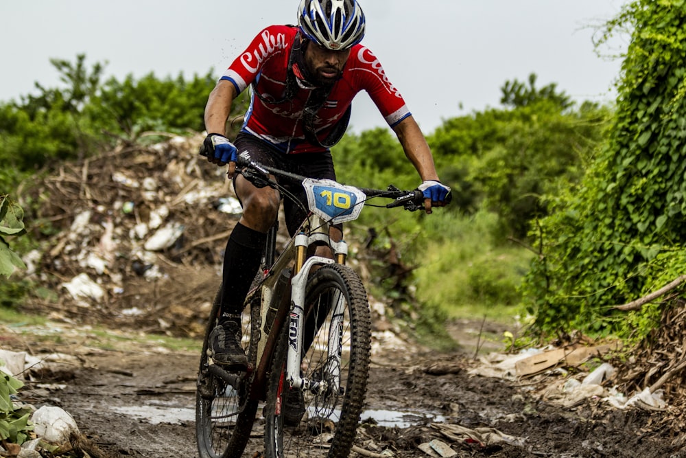 man in red and black bicycle suit riding on blue and white mountain bike during daytime