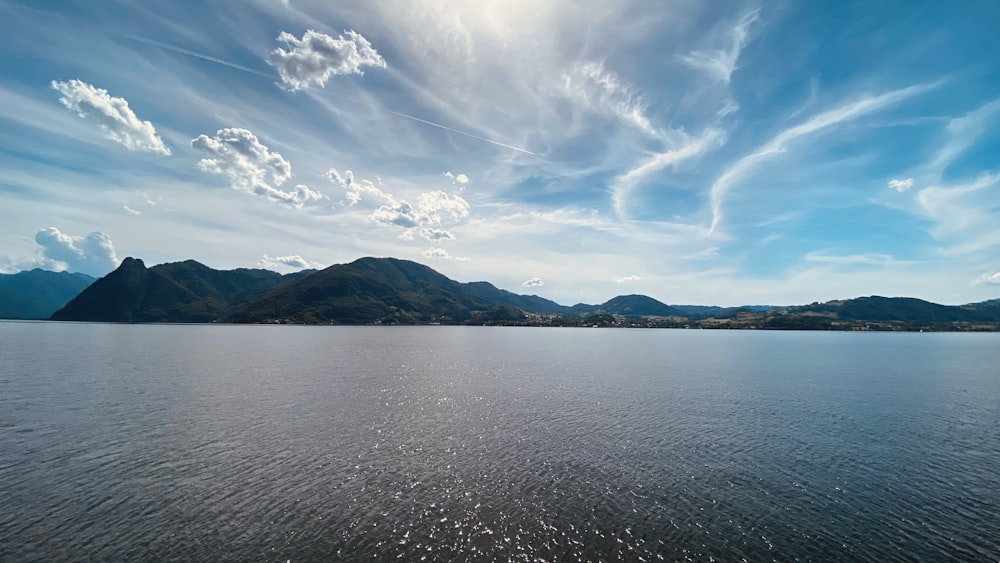 body of water near mountain under blue sky during daytime