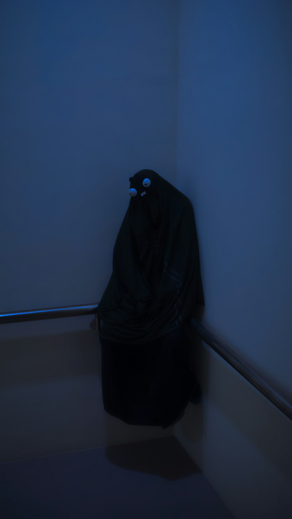 person in black robe standing beside white wall