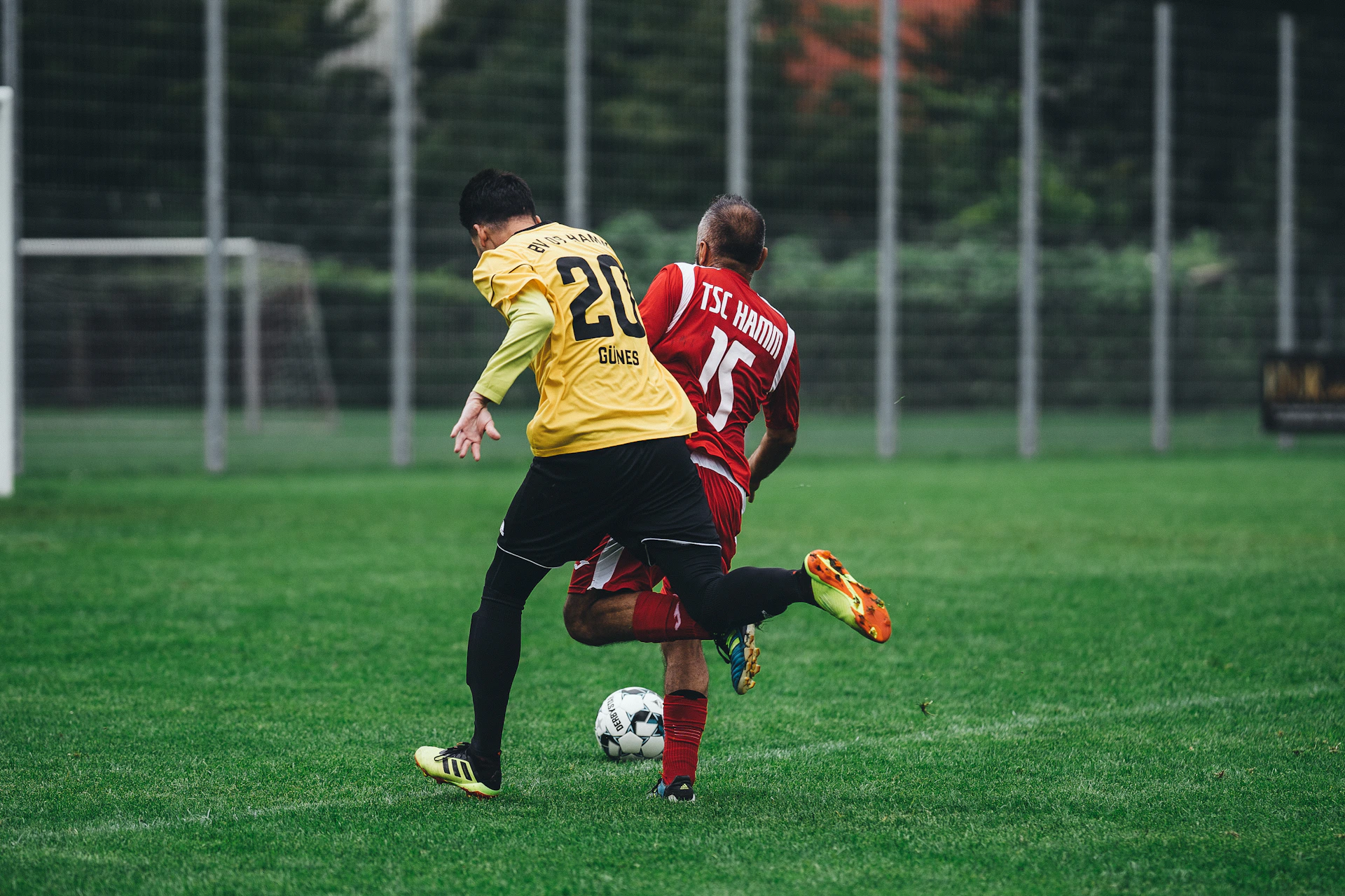 man in red and white jersey shirt playing soccer during daytime