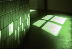 High-contrast neon green-lit audiovisual installation with sharp geometric shadows.