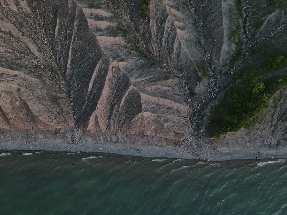 brown rocky mountain beside body of water during daytime