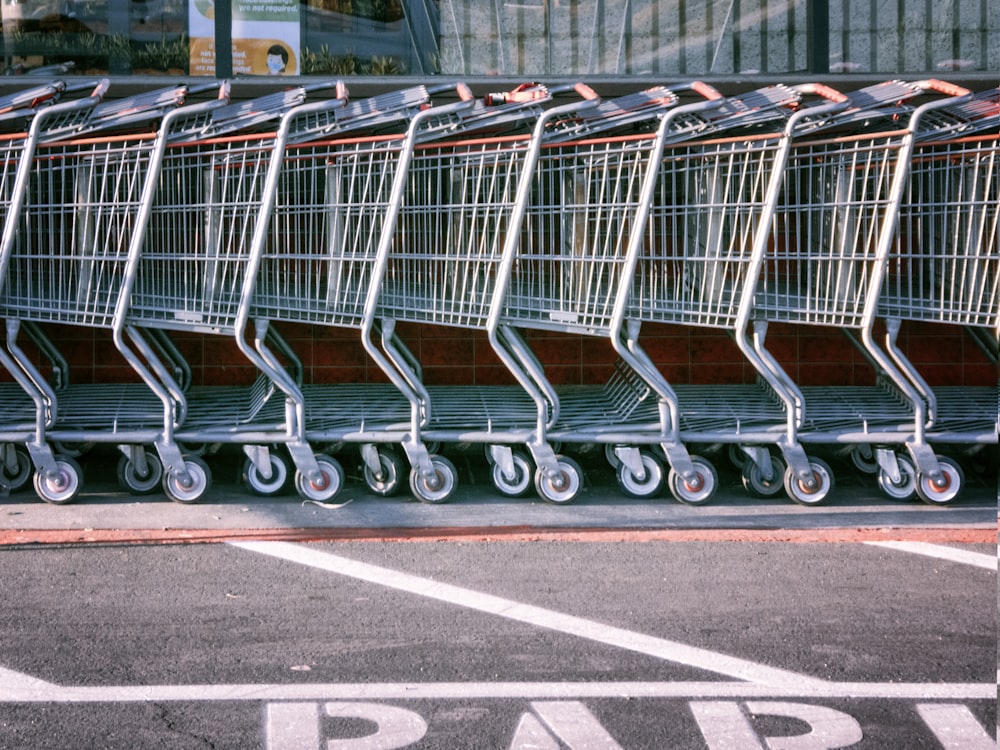 Carrello della spesa rosso e argento sulla strada asfaltata grigia durante il giorno