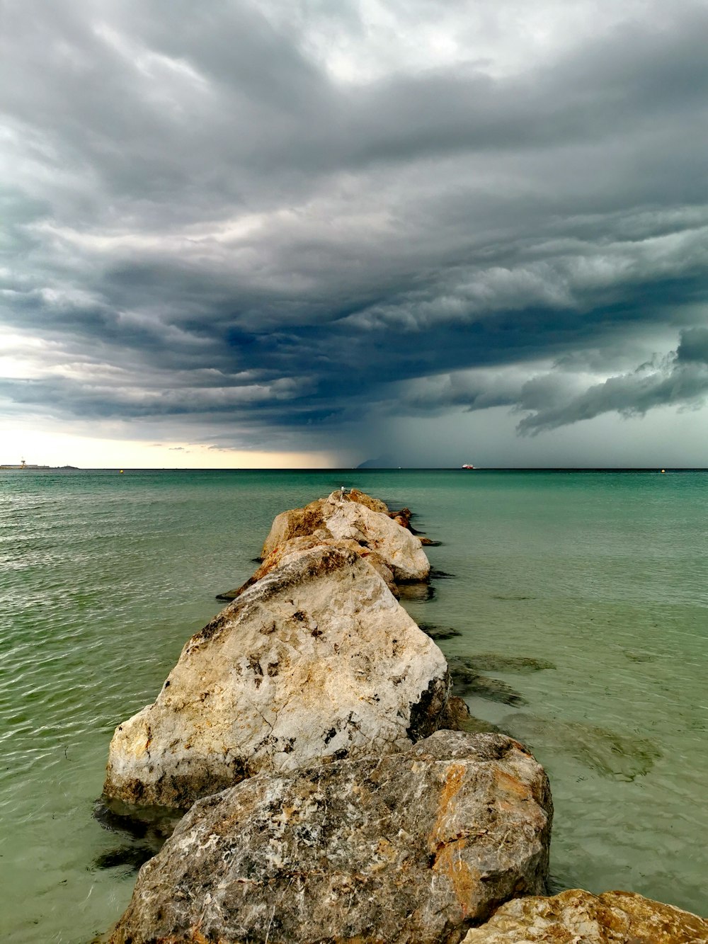 brown rock formation on sea under cloudy sky during daytime