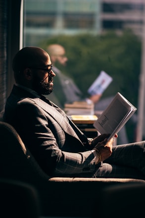 man in black suit jacket reading book