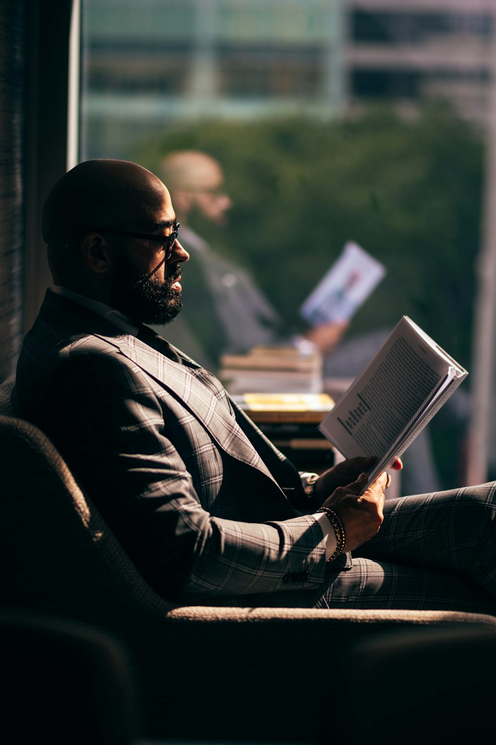 man in black suit jacket reading book