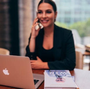 woman in black blazer sitting by the table with macbook