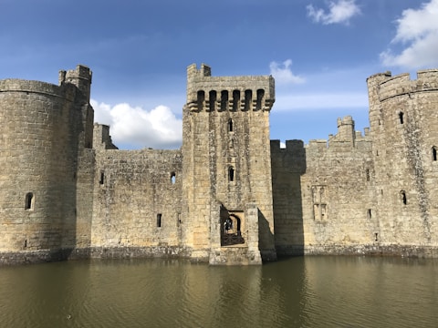 Wide-angle view of Spøttrup Castle with its moat reflecting the stone walls under a bright blue sky.
