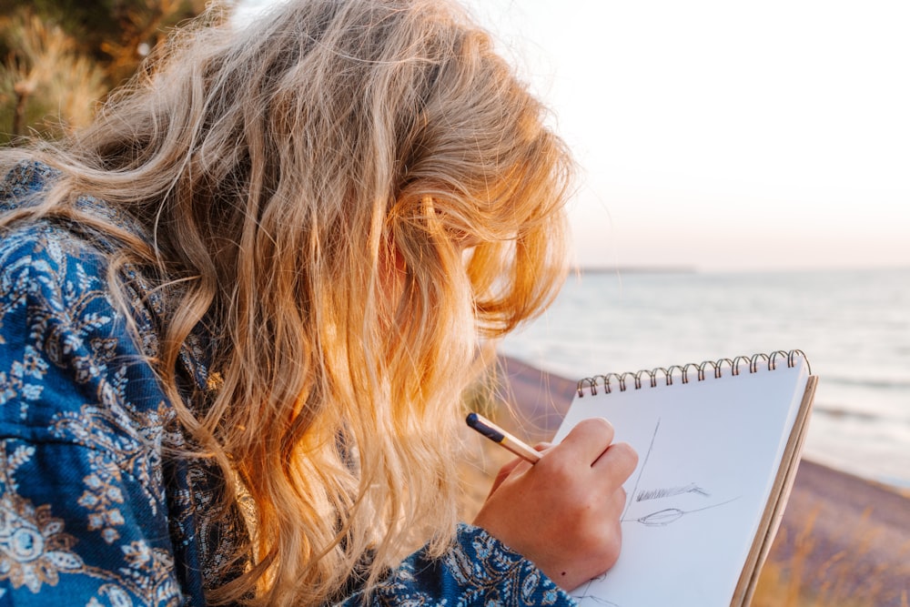 woman in blue and white floral shirt writing on white paper