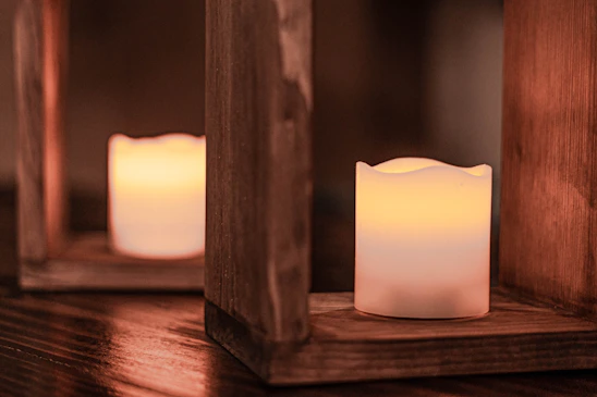 Cozy homemade candles glowing softly on a wooden table with warm natural light.